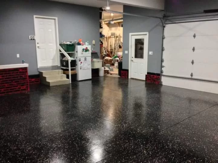 Black Flake Floors installed in a residential garage with a glossy black speckled finish.