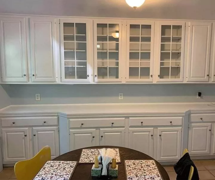 Cabinet Refinishing on white built in dining room cabinets with glass doors and lower storage.