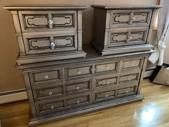 The final result of a furniture paint transformation showing a sleek metallic bronze dresser with crystal knobs.
